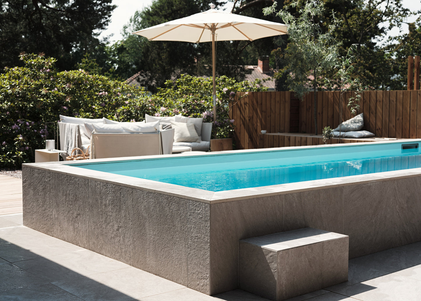 Poolområde där golv har beige grå stenliknande utomhus klinker ifrån Bricmate Quartzit Pearl