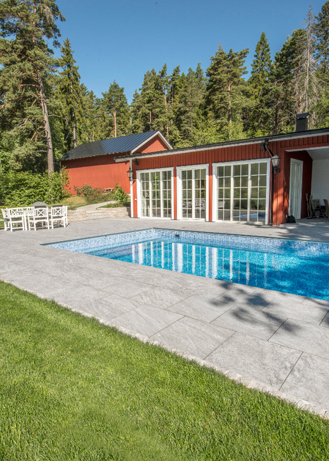 Trädgård klädd i grå mönstrad stenliknande klinker ifrån Bricmate Quartzit Grey